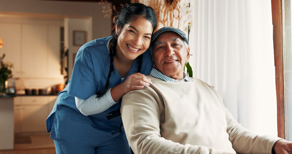 A caregiver smiling warmly beside an older man at home